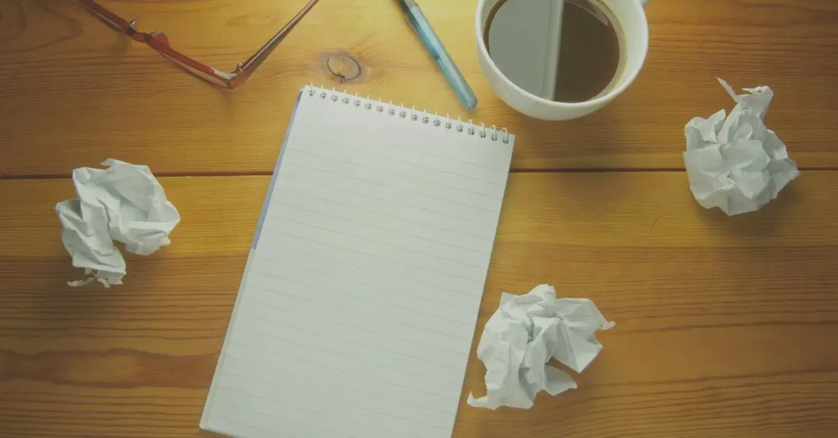 table with empty notepad and wadded up paper expressing writer's block