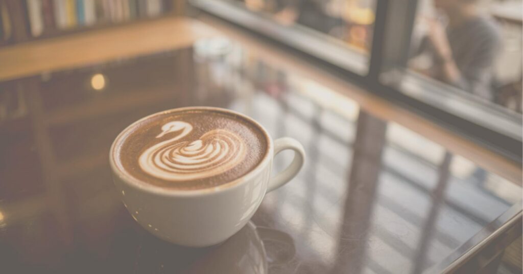 Coffee cup with foam art shaped like swan in writer's cafe