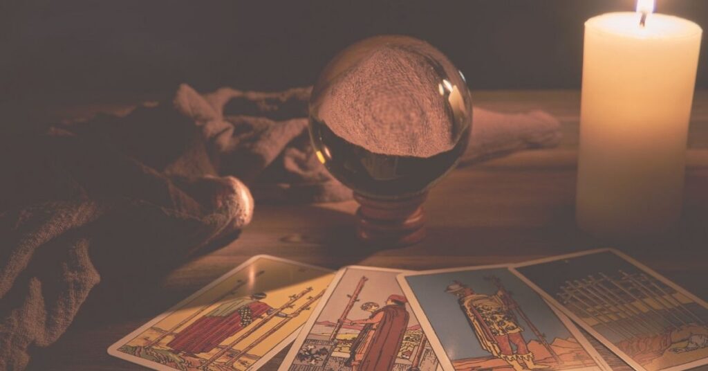 tarot cards next to gazing ball and lit candle